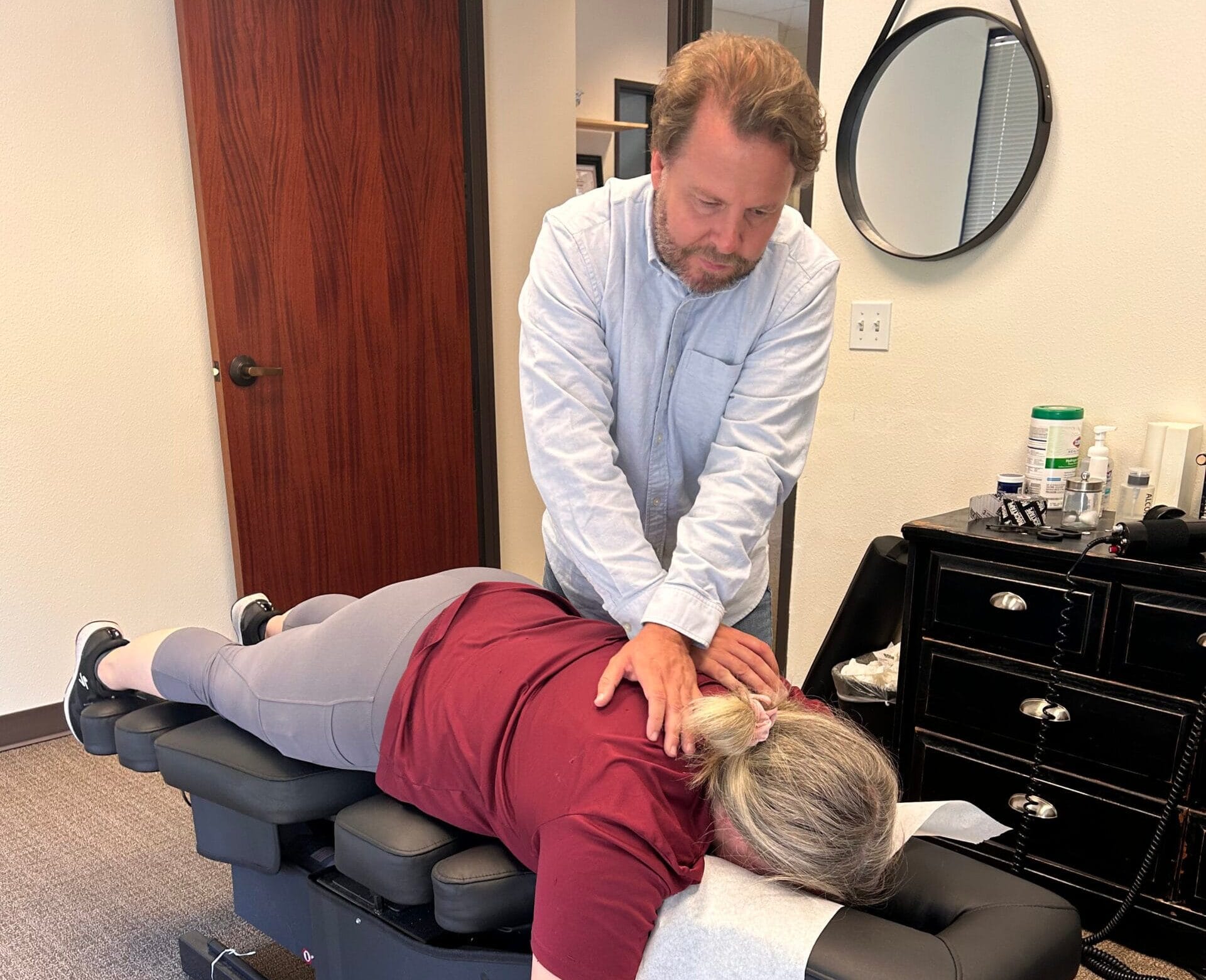 A chiropractor examines a patient's back by placing hands on their spine to assess alignment and posture - Chiropractor Meridian Idaho Dr. Linberg gives a patient an adjustment - Chiropractor Meridian Idaho